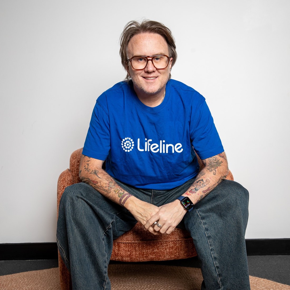 Portrait photo of Jonathan Moran, wearing a Lifeline shirt, sitting down for a conversation.
